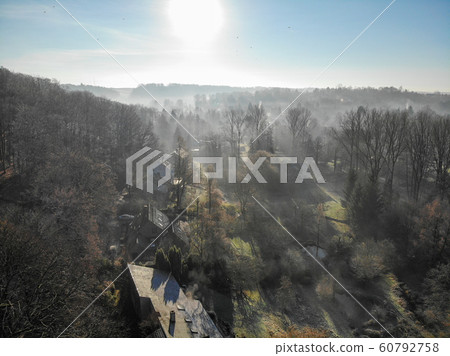 Aerial view of forest and farmland during foggy and cold winter morning with blue sky facing the sun 60792758