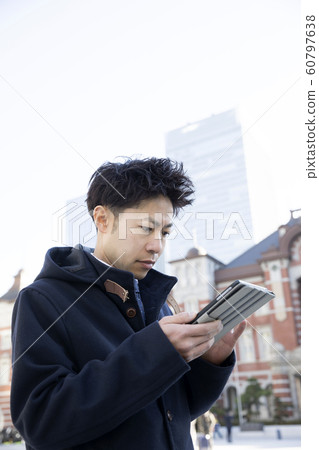Businessman looking seriously at tablet in front of Tokyo station 60797638
