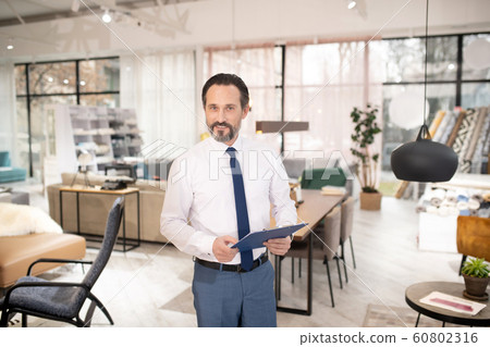 Furniture designer in tie and white shirt holding drawing ih his hands Furniture designer in tie and white shirt holding drawing ih his hands 60802316