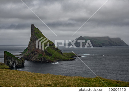 Drangarnir gate, Tindholmur and Mykines under cloudy sky in Faroe Islands Drangarnir gate, Tindholmur and Mykines under cloudy sky in Faroe Islands 60804250