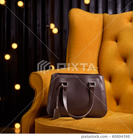 brown leather bag for business woman, on the yellow armchair. 1:1 copy space for text and design. 60804398