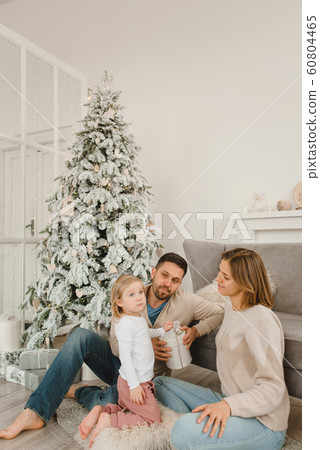 Family Christmas morning in a bright minimalistic living room near the Christmas tree. 60804465