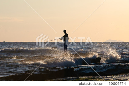 I am fishing on the rocky beach where the rough seas hit. Sanin coast at sunset. Please use for surf fishing PR. Shimane Prefecture 60804754