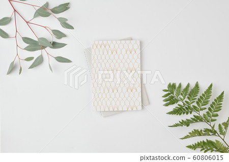 Flatlay of notebook on folded laptop and green leaves against white background Flatlay of notebook on folded laptop and green leaves against white background 60806015