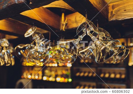 Group of empty wine glasses hanging from metal beams in a bar. Group of empty wine glasses hanging from metal beams in a bar. 60806302