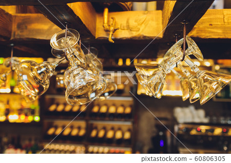 Group of empty wine glasses hanging from metal beams in a bar. Group of empty wine glasses hanging from metal beams in a bar. 60806305