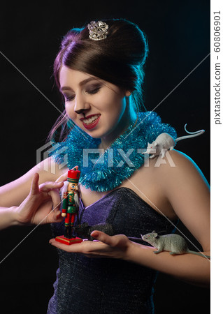 girl in Mouse Queen costume plays with Nutcracker toy on black background girl in Mouse Queen costume plays with Nutcracker toy on black background 60806901