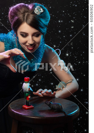 girl in Mouse Queen costume plays with Nutcracker toy on stars background girl in Mouse Queen costume plays with Nutcracker toy on stars background 60806902