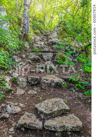 Path with steps carved into a sheer cliff at sunset 60807654