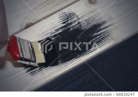 painting a wooden Board in black. black paint and brush. painting a wooden Board in black. black paint and brush. 60810247