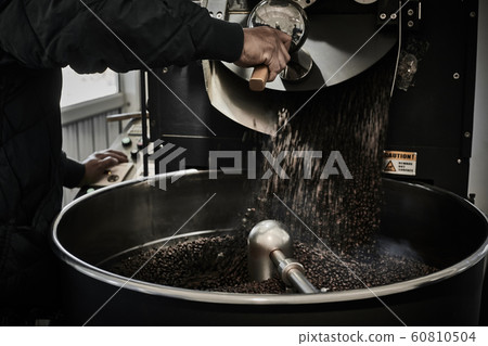 Freshly roasted coffee beans pouring from a large 60810504