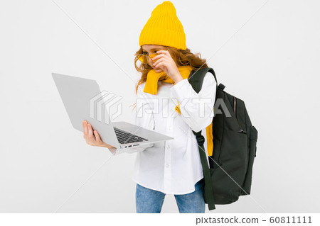 student girl in casual clothes with a backpack and with a laptop in her hands walking and reading student girl in casual clothes with a backpack and with a laptop in her hands walking and reading 60811111