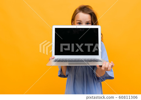 charming girl peeks out at a laptop with a mockup on a yellow background charming girl peeks out at a laptop with a mockup on a yellow background 60811306