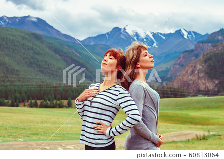 two girls stand against the mountains 60813064