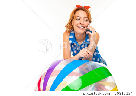 girl in shorts and a t-shirt talking on the phone and leans on an inflatable ball on a white girl in shorts and a t-shirt talking on the phone and leans on an inflatable ball on a white 60813154