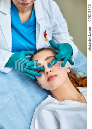 Lady with plaster on nose, doctor examining patients face after plastic surgery 60815806