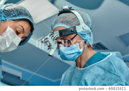Two surgeons in protective uniform during the operation, on background of surgical room. Point of view shot 60815811