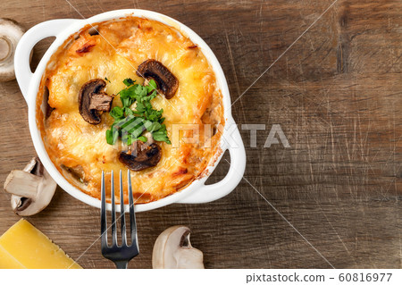 Casserole with chicken, mushrooms and cheese known in Russia as julienne in white bowl with herbs on a wooden board, top view, flat lay, copy space Casserole with chicken, mushrooms and cheese known in Russia as julienne in white bowl with herbs on a wooden board, top view, flat lay, copy space 60816977