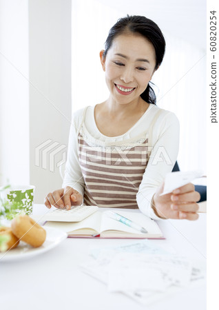 Middle woman keeping a household account book 60820254
