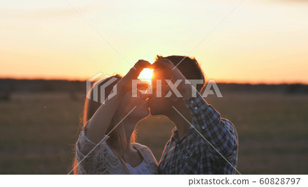 A couple in love makes a heart shape from their hands and kisses. A couple in love makes a heart shape from their hands and kisses. 60828797
