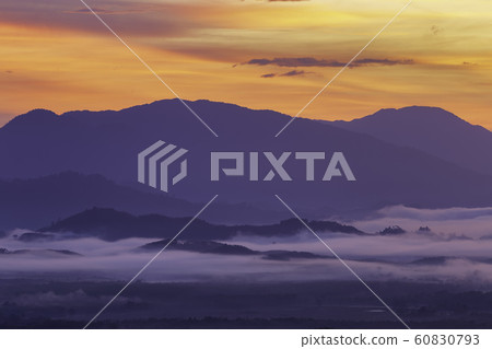 A morning view of a mist-covered mountain and the sun rising from the mountains. A morning view of a mist-covered mountain and the sun rising from the mountains. 60830793