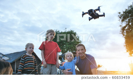 A father with children is watching a working drone. 60833459
