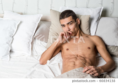 Young handsome man rest in bed. Sexy naked guy is 60834138