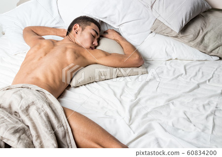 Young handsome man rest in bed. Sexy naked guy is 60834200