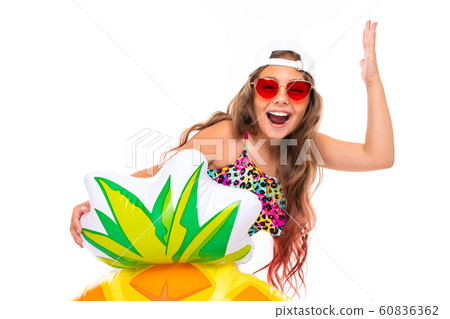 joyful attractive girl in a swimsuit and a baseball cap with a rubber ring on a white background 60836362