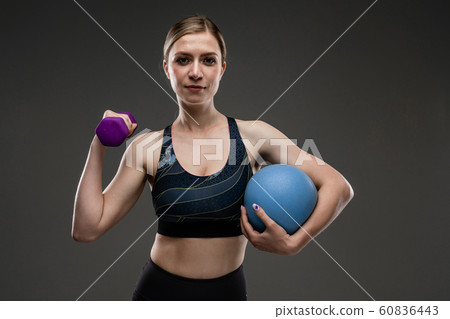 Sport caucasian girl with slim figure do exercises with blue ball and purple dumddell isolated on Sport caucasian girl with slim figure do exercises with blue ball and purple dumddell isolated on 60836443