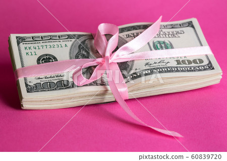 a bundle of dollars tied with a pink ribbon a bundle of dollars tied with a pink ribbon 60839720