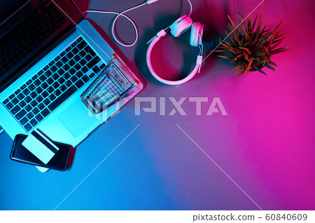 Laptop with headphones, custumers trolley, phone and payment card on the table in modern neon colors. 60840609