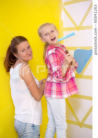 mom and daughter paints the wall 60841263