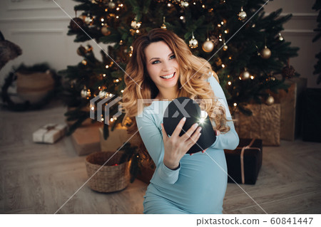 Happy pregnancy woman opening holiday light gift 60841447