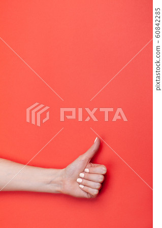 close-up female hand shows thumb up on red background 60842285