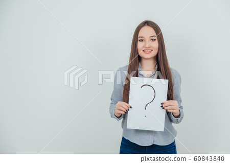 Inquisitive asian student girl holding a sheet of paper with question mark written on it, smiling at the camera. Inquisitive asian student girl holding a sheet of paper with question mark written on it, smiling at the camera. 60843840