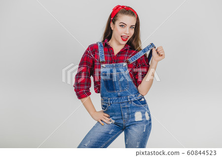 Cute girl standing, pulling up her suspender, keeping one hand on her hip, looking seducively at the camera. Cute girl standing, pulling up her suspender, keeping one hand on her hip, looking seducively at the camera. 60844523