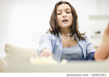 heerful and confused woman is reaching after a pile of pop corn. Copy space. heerful and confused woman is reaching after a pile of pop corn. Copy space. 60845263