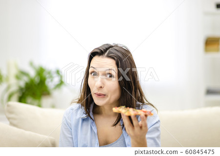 Brunette woman is positively shocked how tasty pizza is, and raises her eyebrows up. Closed up. Brunette woman is positively shocked how tasty pizza is, and raises her eyebrows up. Closed up. 60845475