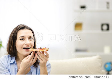 Attractive brunette woman is looking at straight at the camera. She wants to eat pizza slice and smiles widely, on light background. Close up. Copy space. Attractive brunette woman is looking at straight at the camera. She wants to eat pizza slice and smiles widely, on light background. Close up. Copy space. 60845517