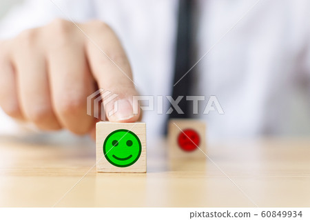 Hand of a businessman chooses a smiley face on wood block cube 60849934