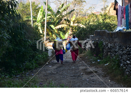 尼泊爾博卡拉尼泊爾婦女提著竹basket，提著行李沿著山路的農村住所 60857614
