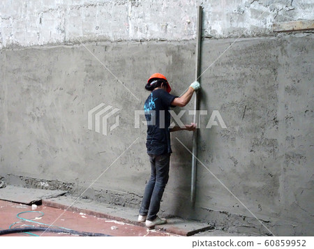 Construction workers plastering building wall using cement plaster with mix of cement, sand & lime at the construction site. 60859952