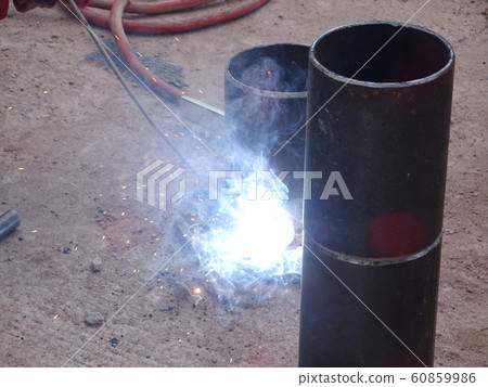 Construction workers welding pipes at the construction site.  60859986
