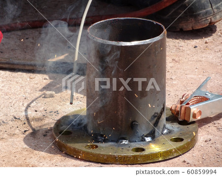 Construction workers welding pipes at the construction site.  60859994