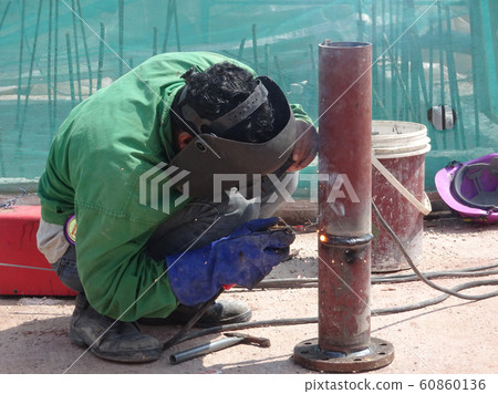 Construction workers welding pipes at the construction site.  60860136
