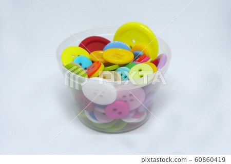 Colourful and various size of cloth button inside clear plastic container isolated on white background Colourful and various size of cloth button inside clear plastic container isolated on white background 60860419