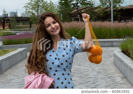 Young positive Woman Holding Oranges Young positive Woman Holding Oranges 60863892