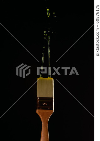 Brushes with spreading yellow paint on blank black background 60876178