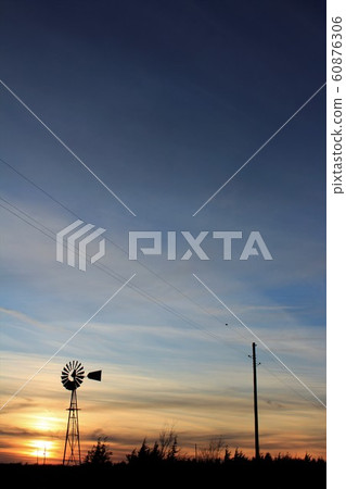 Kansas colorful Sunset with a colorful sky,tree's and a Windmill silhouette. Kansas colorful Sunset with a colorful sky,tree's and a Windmill silhouette. 60876306